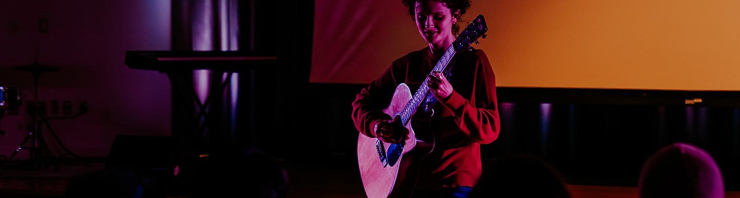 student playing accoustic guitar