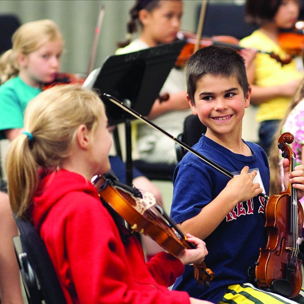 Kids smiling and practicing violin